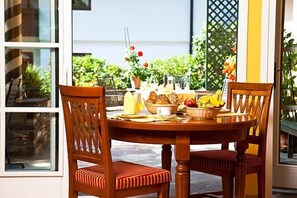 A dining table with chairs, a basket of bread, a bowl of fruit, and a pitcher of juice. - Aparthotel Landhaus St. Joseph (Mayrhofen)