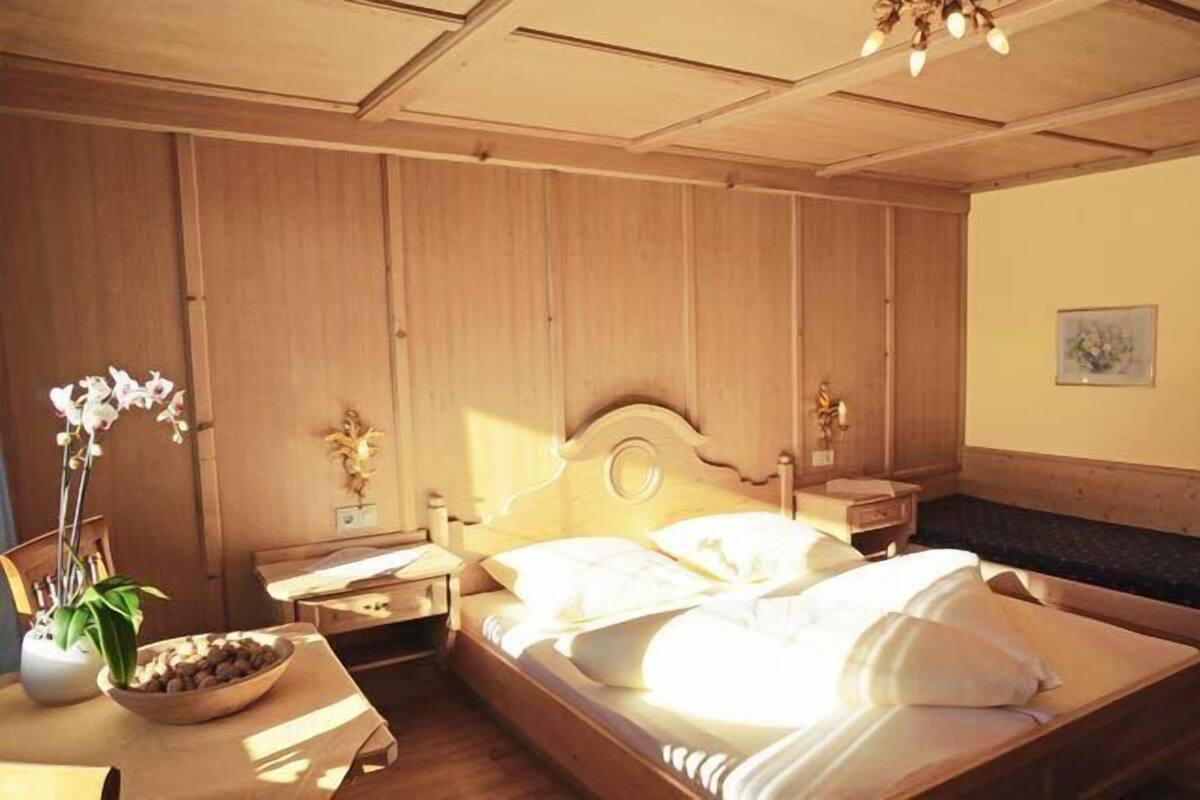 Une chambre à coucher aux murs lambrissés, avec un lit, des tables de chevet et une petite table de nuit.