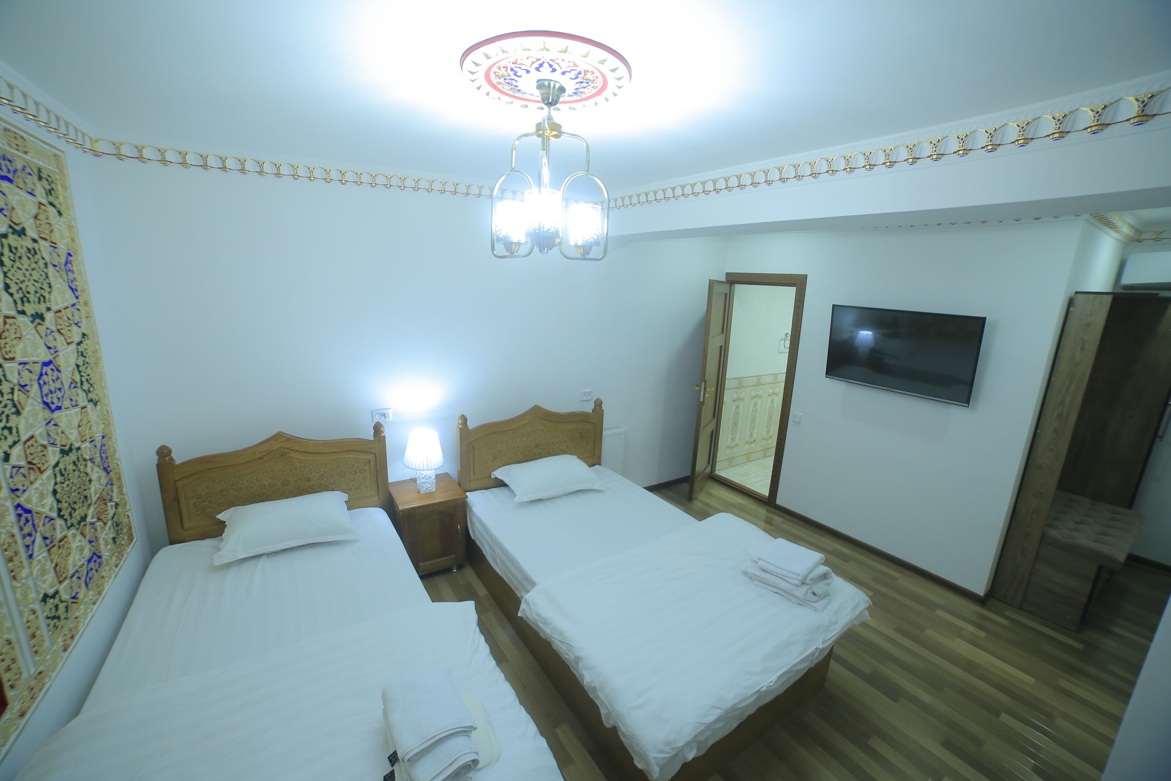 A hotel room with two beds, a television, and a mirror.