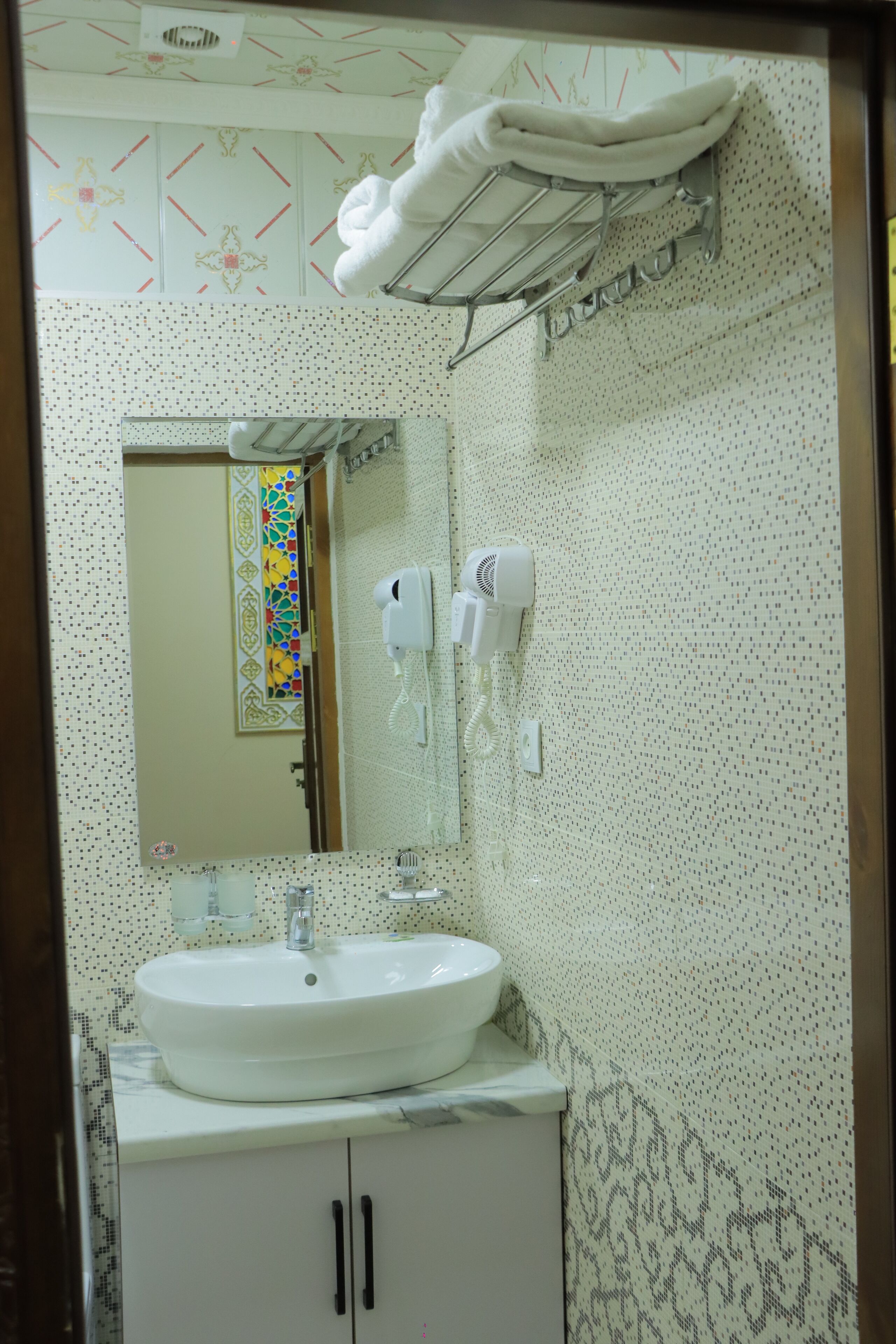 A bathroom with a white sink, a towel rack, a hairdryer, and a mirror.