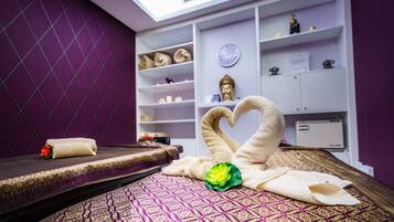Experience a serene spa setting with a massage table, Buddha statue, and calming ambiance.