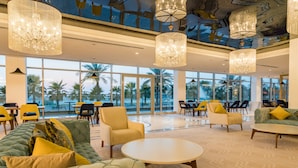 A spacious lobby with large windows, modern furniture, and decorative chandeliers.