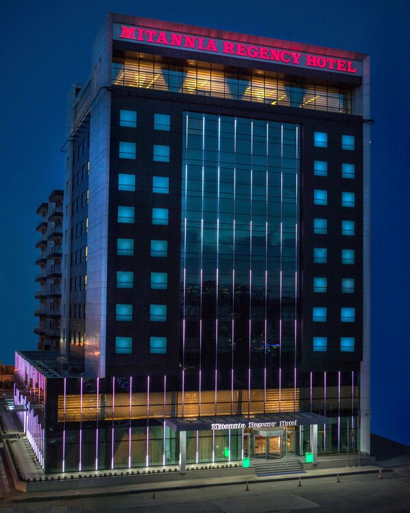 The exterior of the Mitanni Regency Hotel with a modern glass facade and illuminated signage. - Mitannia Regency Hotel (Diyarbakir)