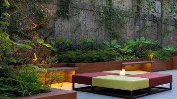 A modern outdoor seating area with cushioned benches and a candle centerpiece.