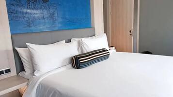 A modern hotel room with a large bed, a blue artwork on the wall, and a wooden wardrobe.