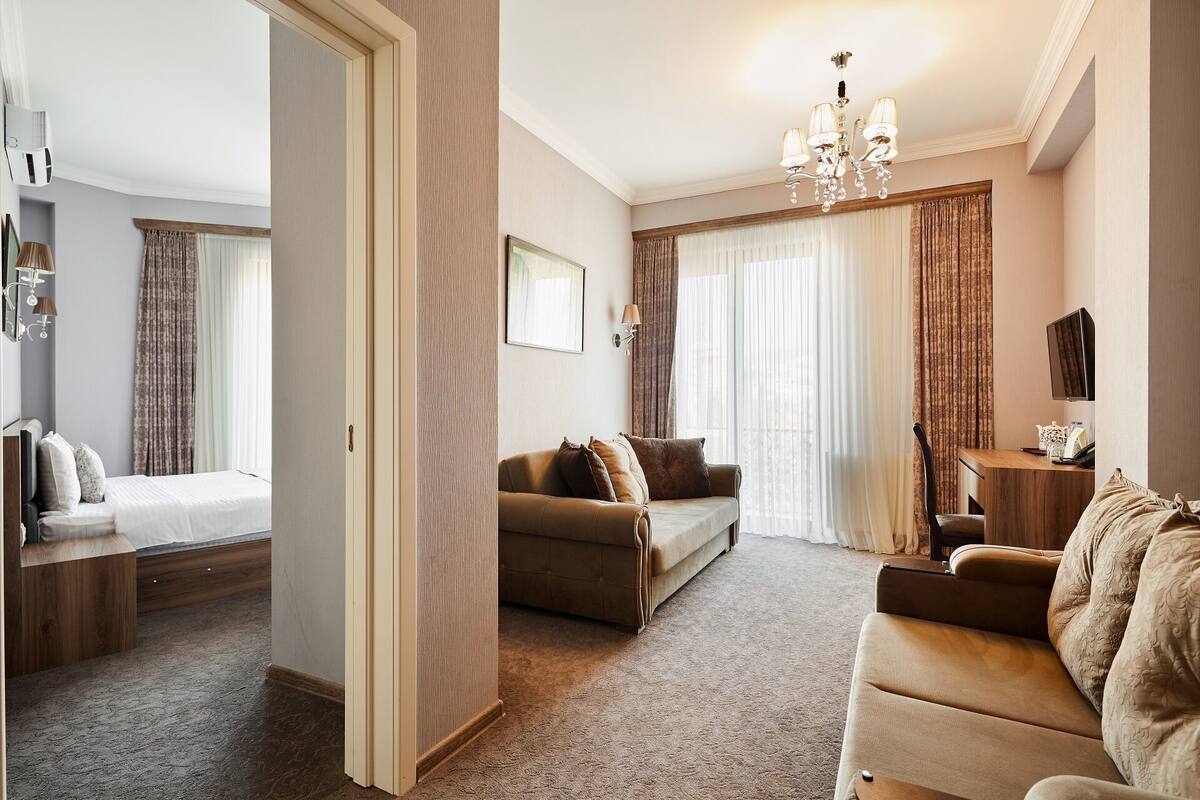 A hotel room with a bed, a sofa, a desk, and a TV.
