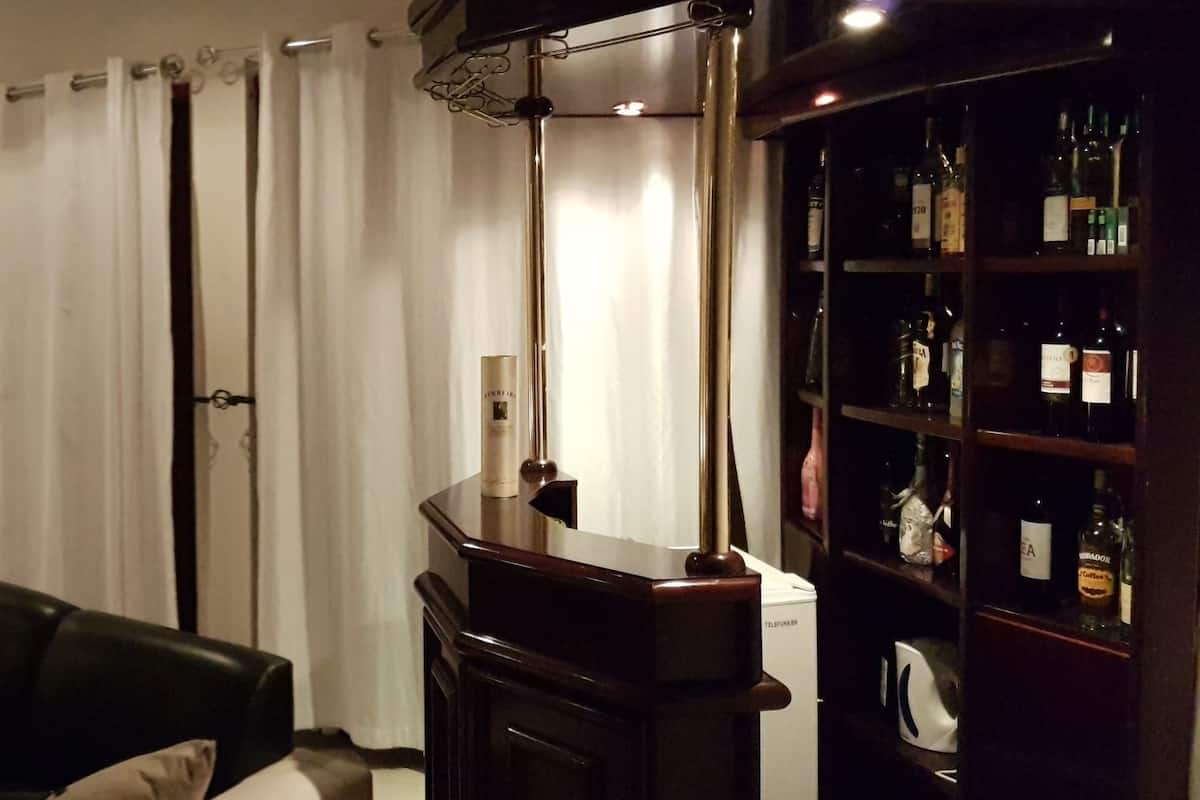 A hotel room with a bed, bedside tables, a desk, a chair, a wardrobe, and a minibar.