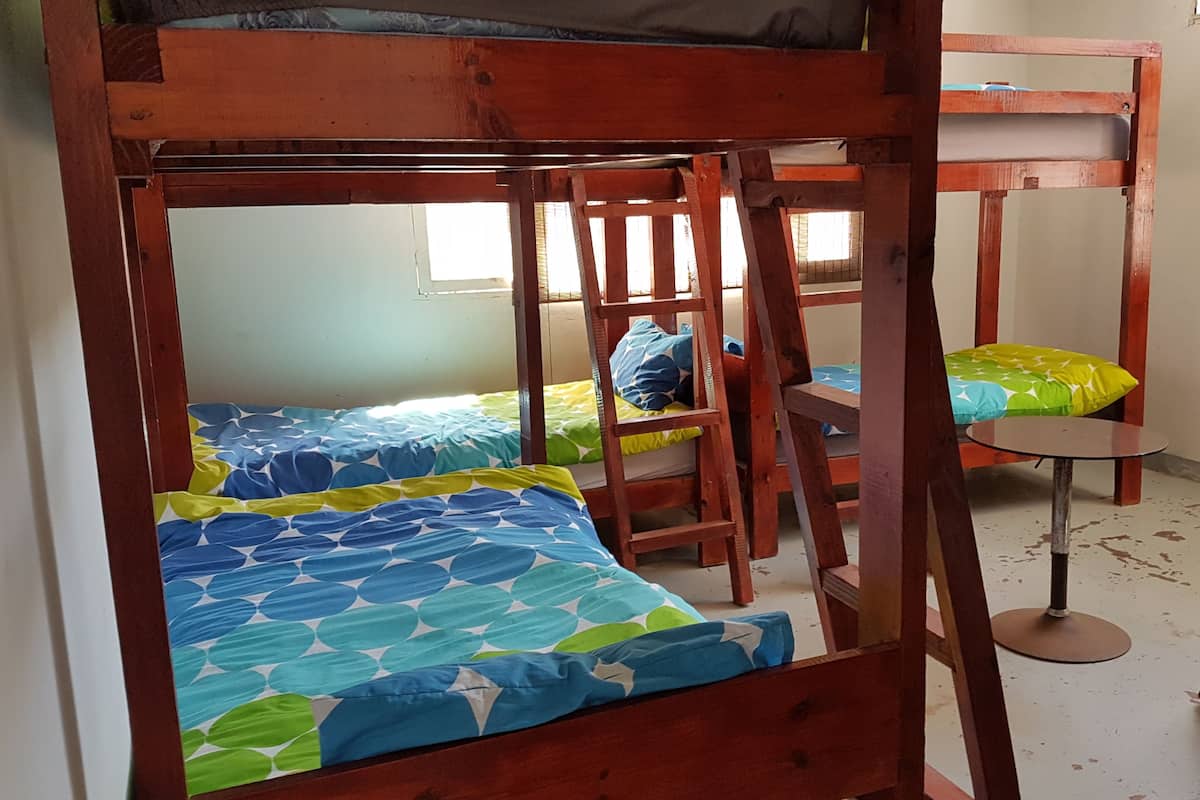 A bunk bed room with two beds, a small table, and a ladder.