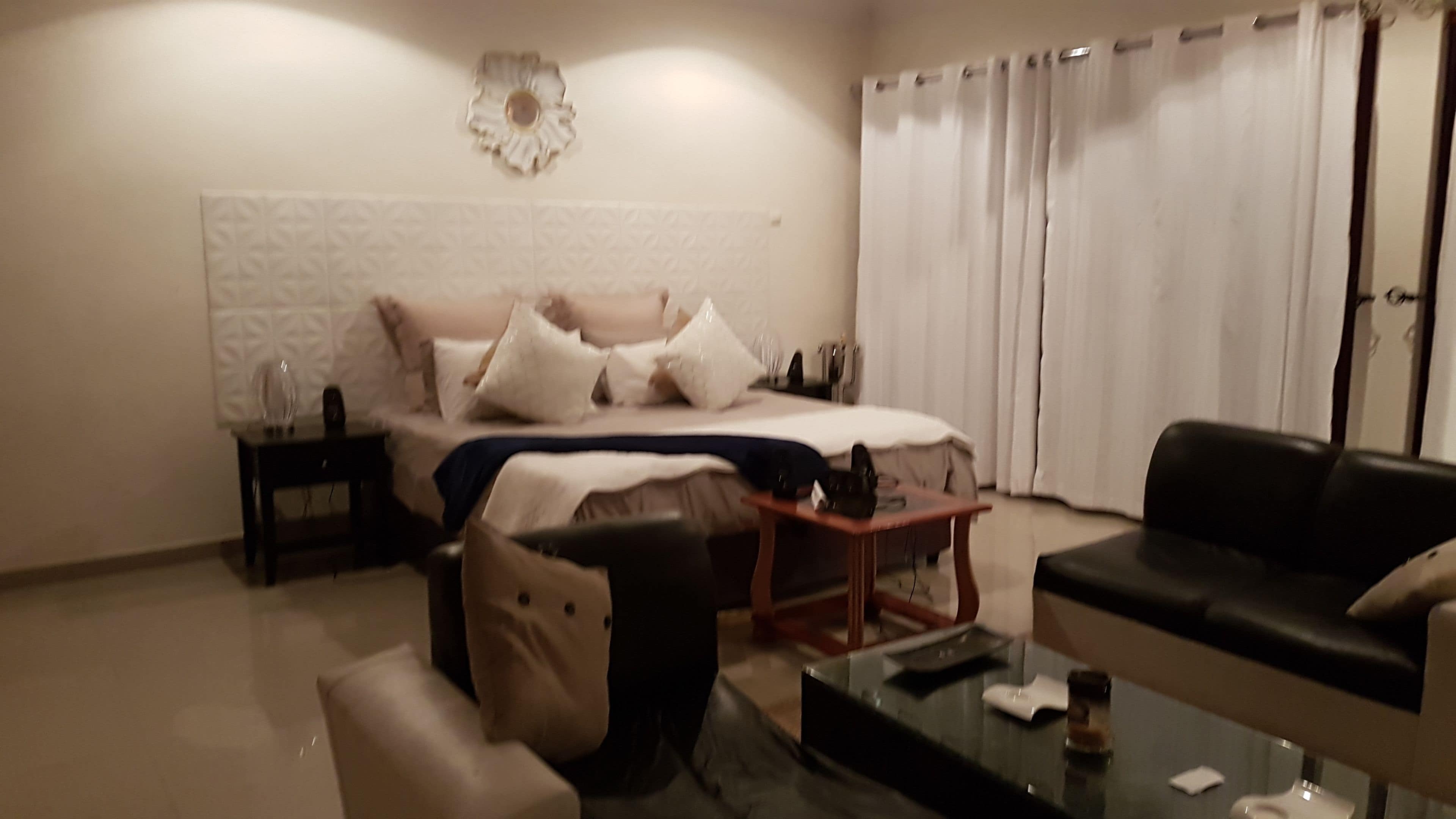 Un dormitorio moderno con cama, mesita de noche, mesa de centro y sofá.