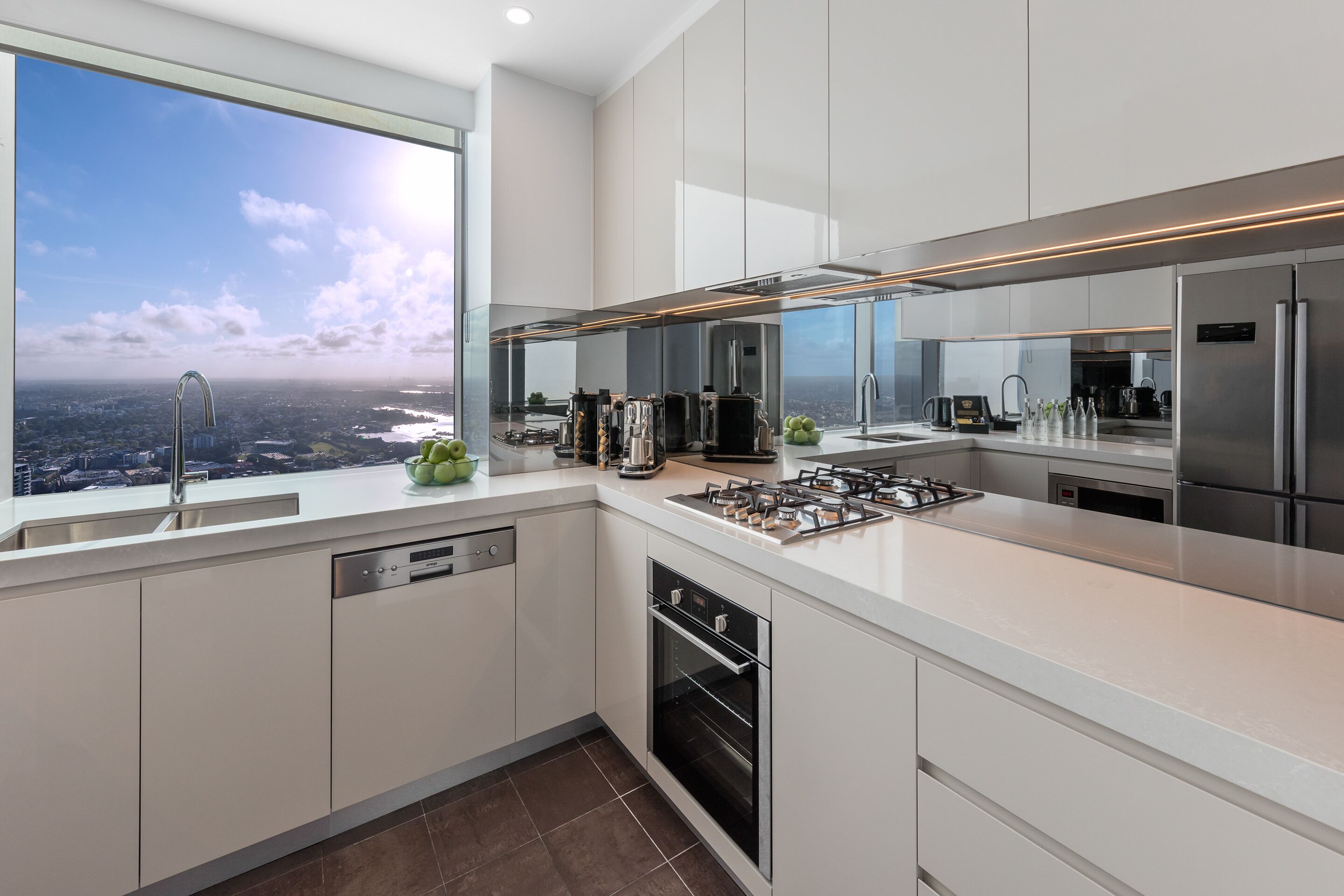 A modern kitchen with a large window, stainless steel appliances, and a city view.