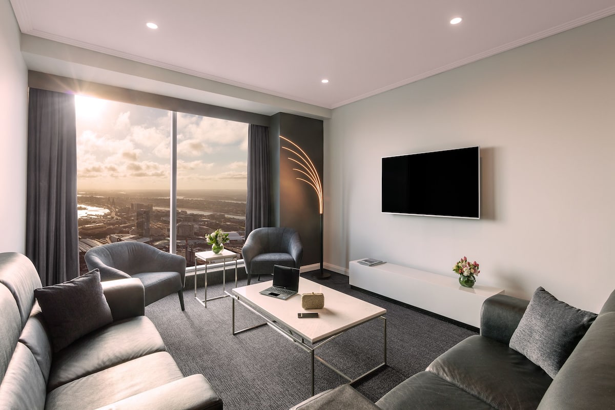 A modern living room with a sofa, armchairs, a coffee table, and a TV mounted on the wall.