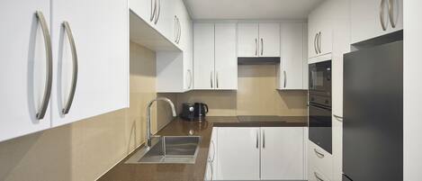 A modern kitchen with white cabinets, stainless steel appliances, and a granite countertop.