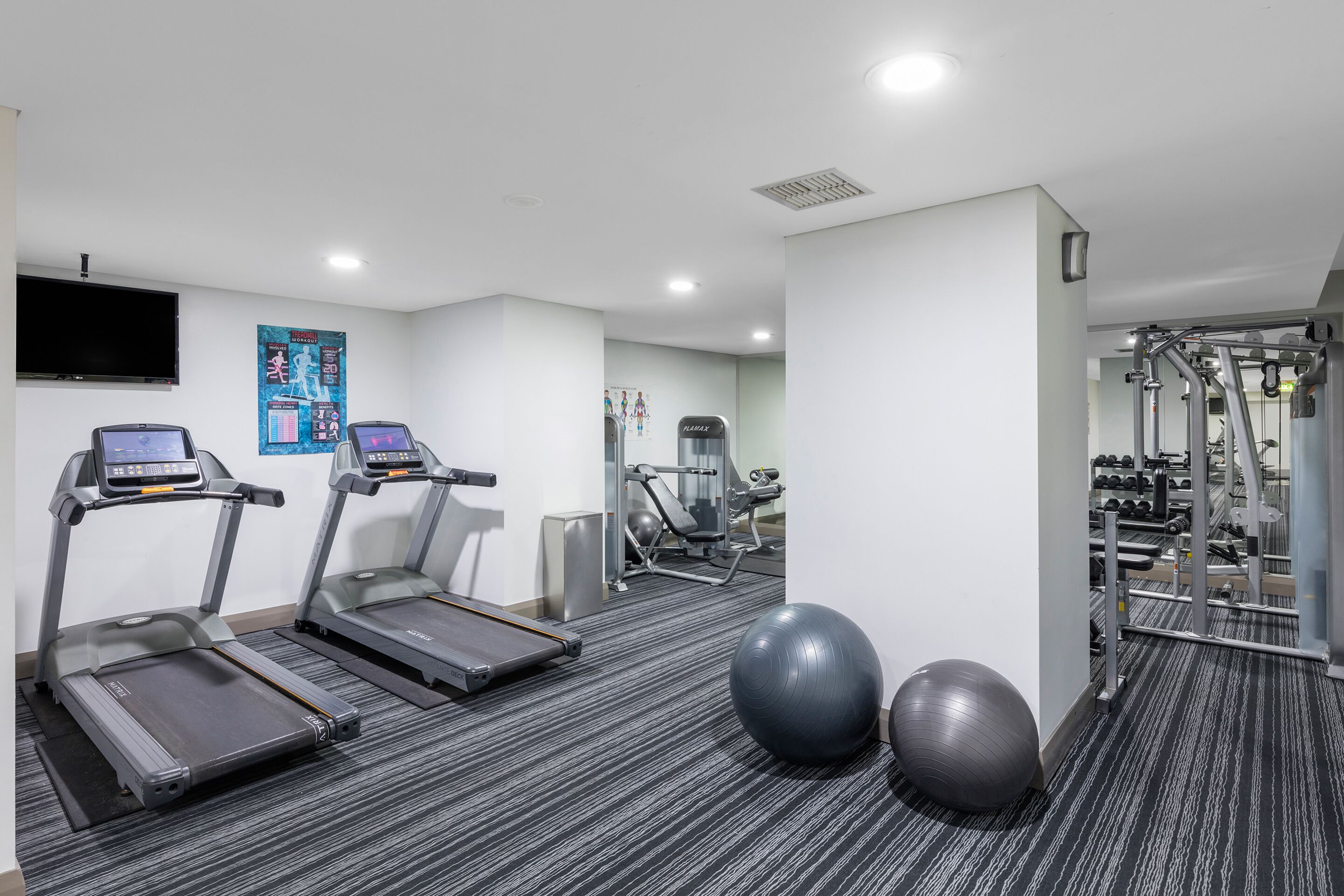 A gym with treadmills, exercise balls, and weight equipment.