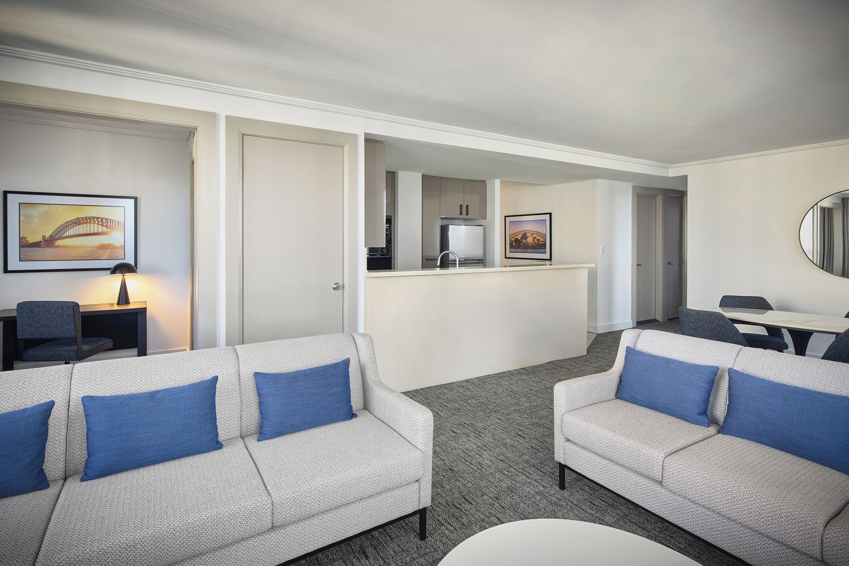 Une chambre d’hôtel avec deux canapés, une table à manger, un coin cuisine et des œuvres d’art accrochées aux murs.