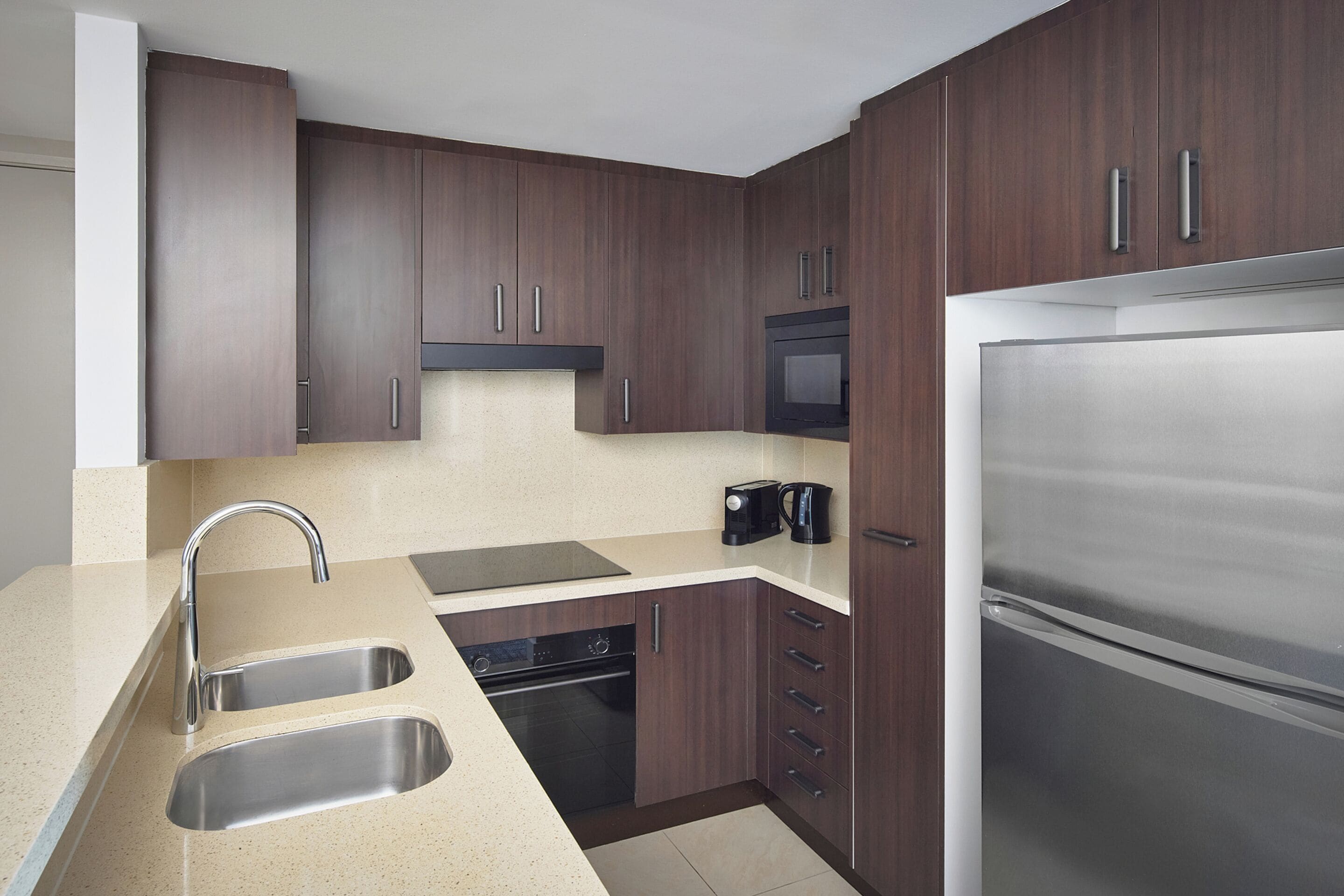 A modern kitchen with dark wood cabinets, stainless steel appliances, and a double sink.