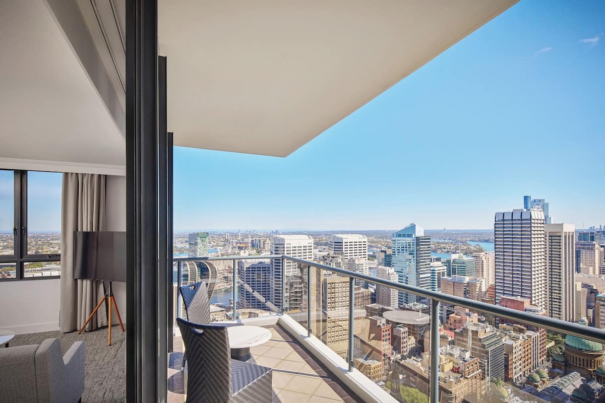 A modern hotel room with a balcony overlooking a cityscape.