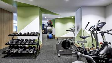 A gym with exercise equipment including dumbbells, a stationary bike, and a rowing machine.