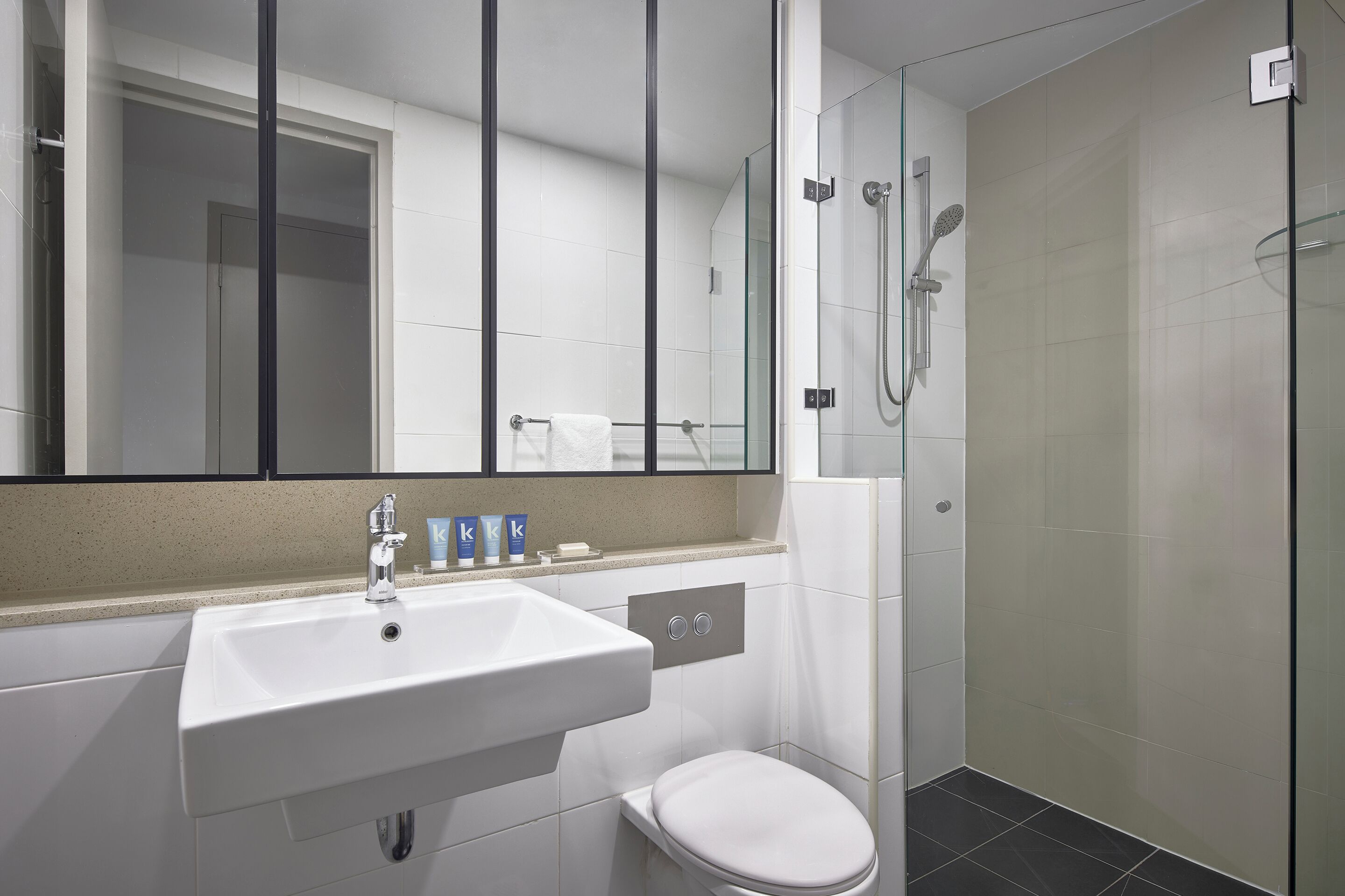 A bathroom with a white sink, mirror, and toilet.