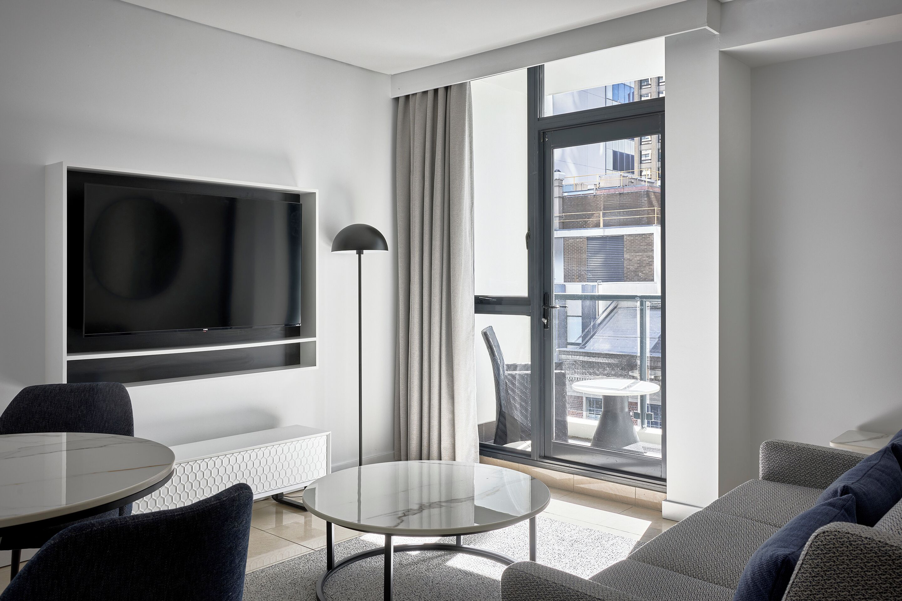 A modern living room with a flat-screen TV, a round table, and a sofa.