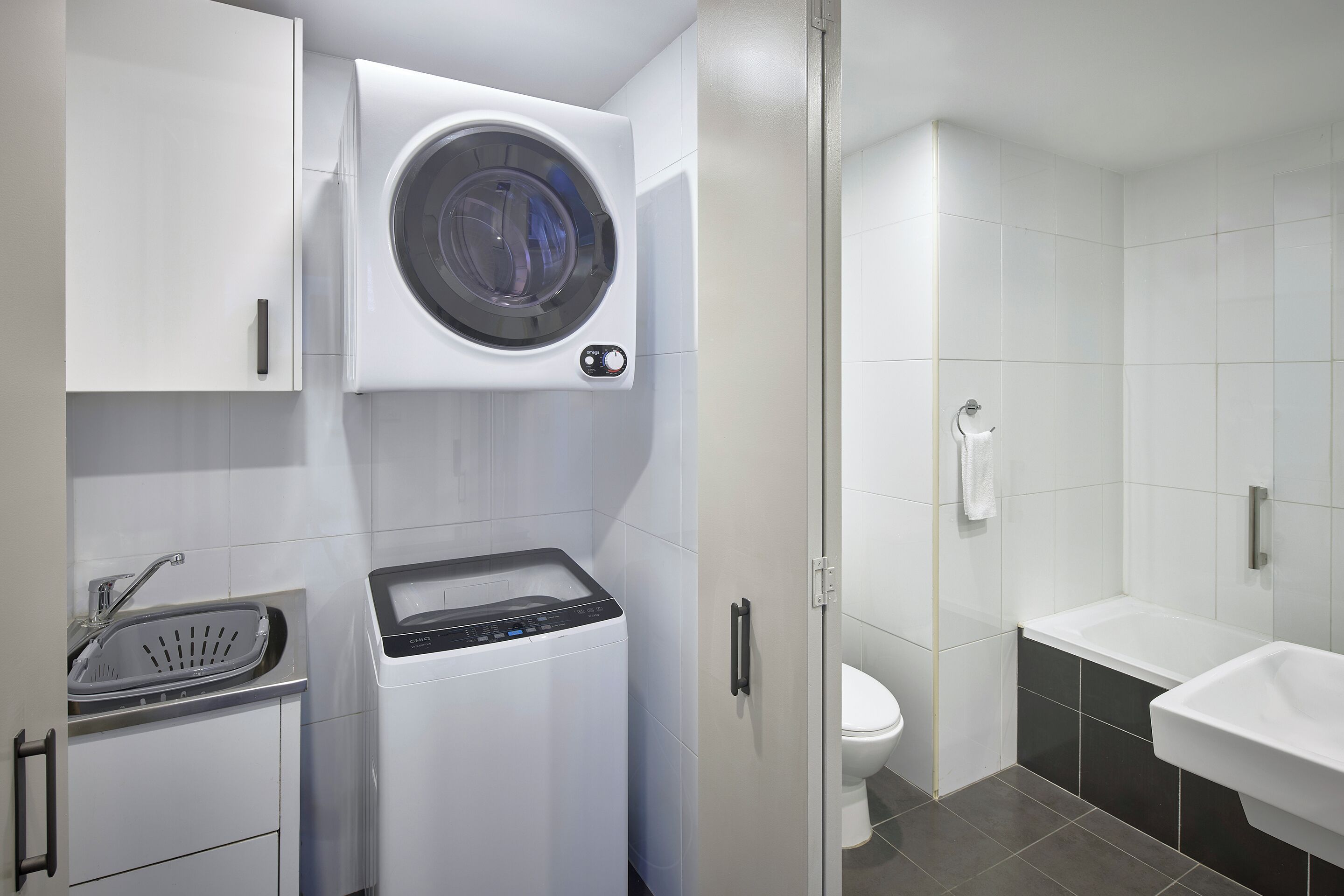 A modern bathroom with a built-in washing machine, a toilet, and a sink.
