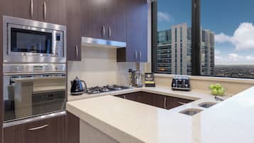 A modern kitchen with stainless steel appliances, a large window with a city view, and a countertop with a kettle and toaster.