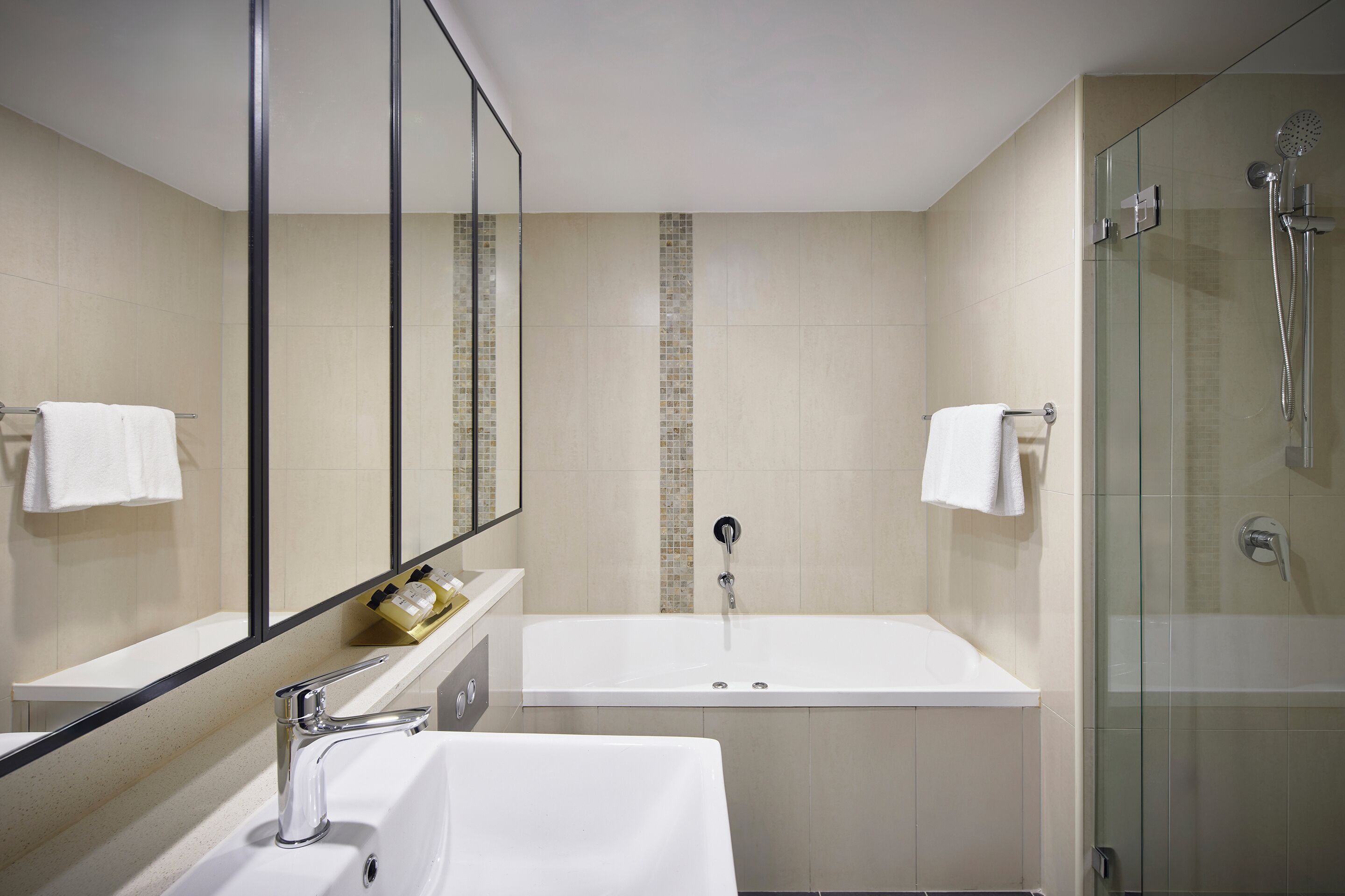 A modern bathroom with a large bathtub, a glass-enclosed shower, and a vanity with a mirror.