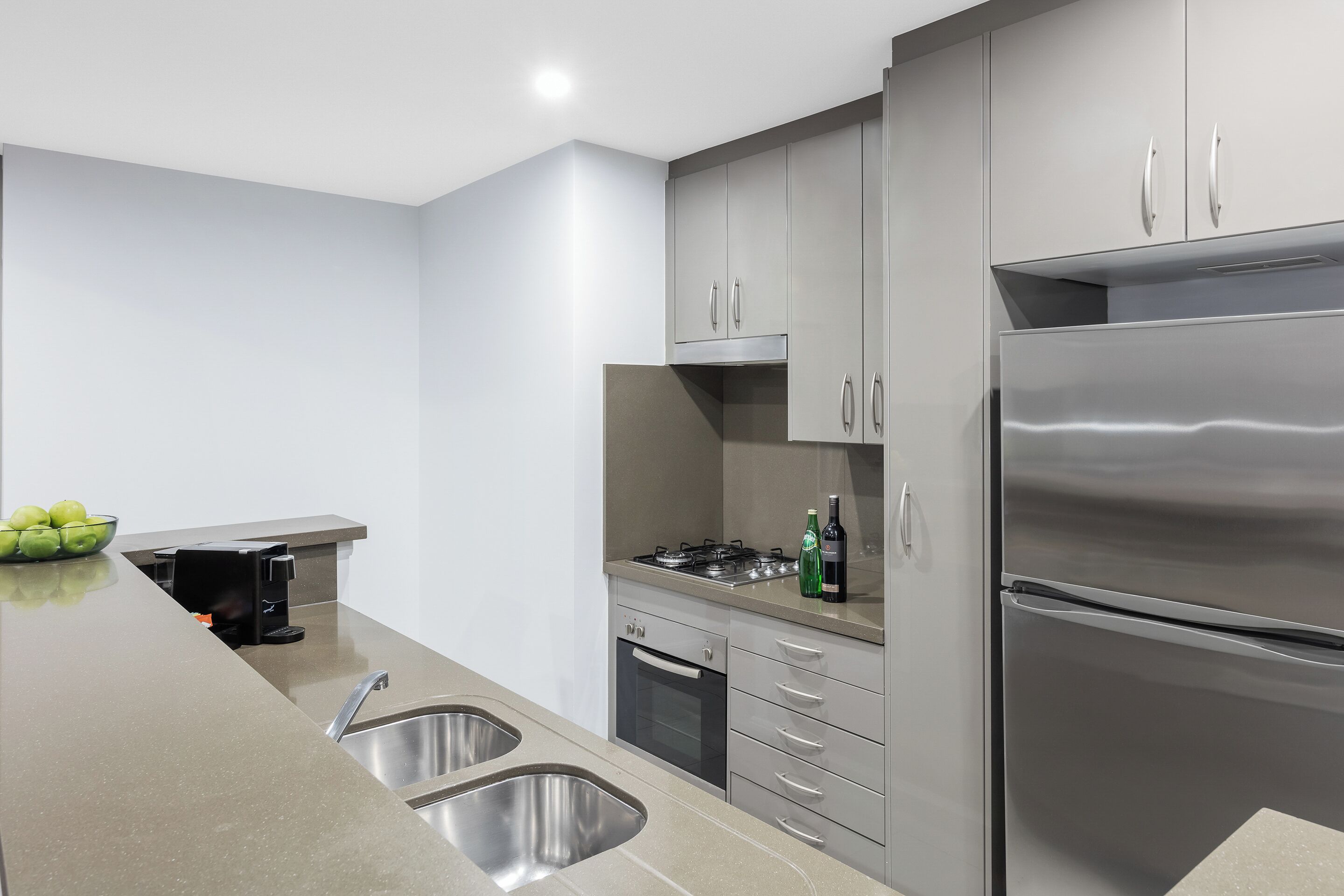 A modern kitchen with stainless steel appliances, a double sink, and grey cabinetry.