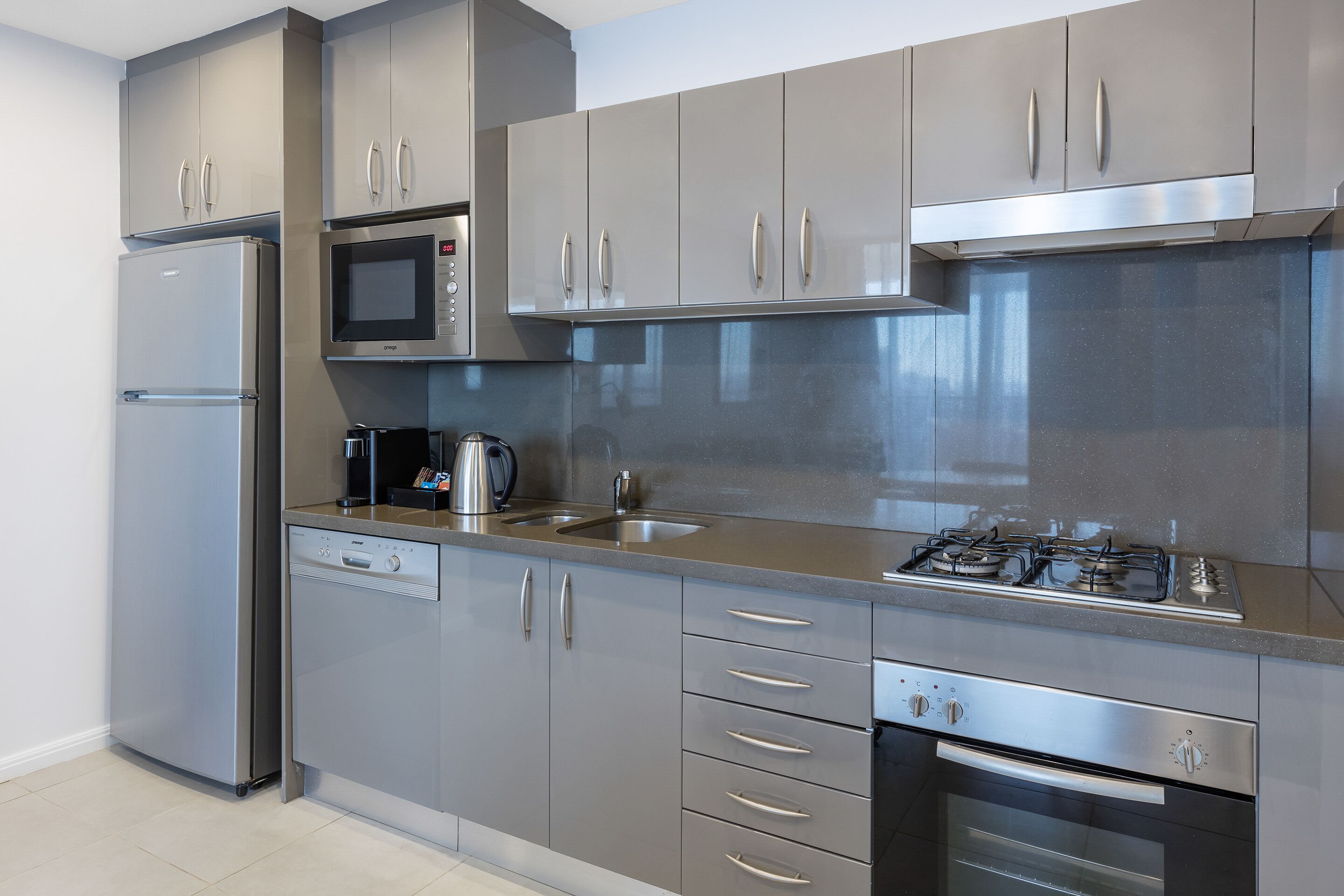 A modern kitchen with stainless steel appliances, grey cabinetry, and a built-in microwave.