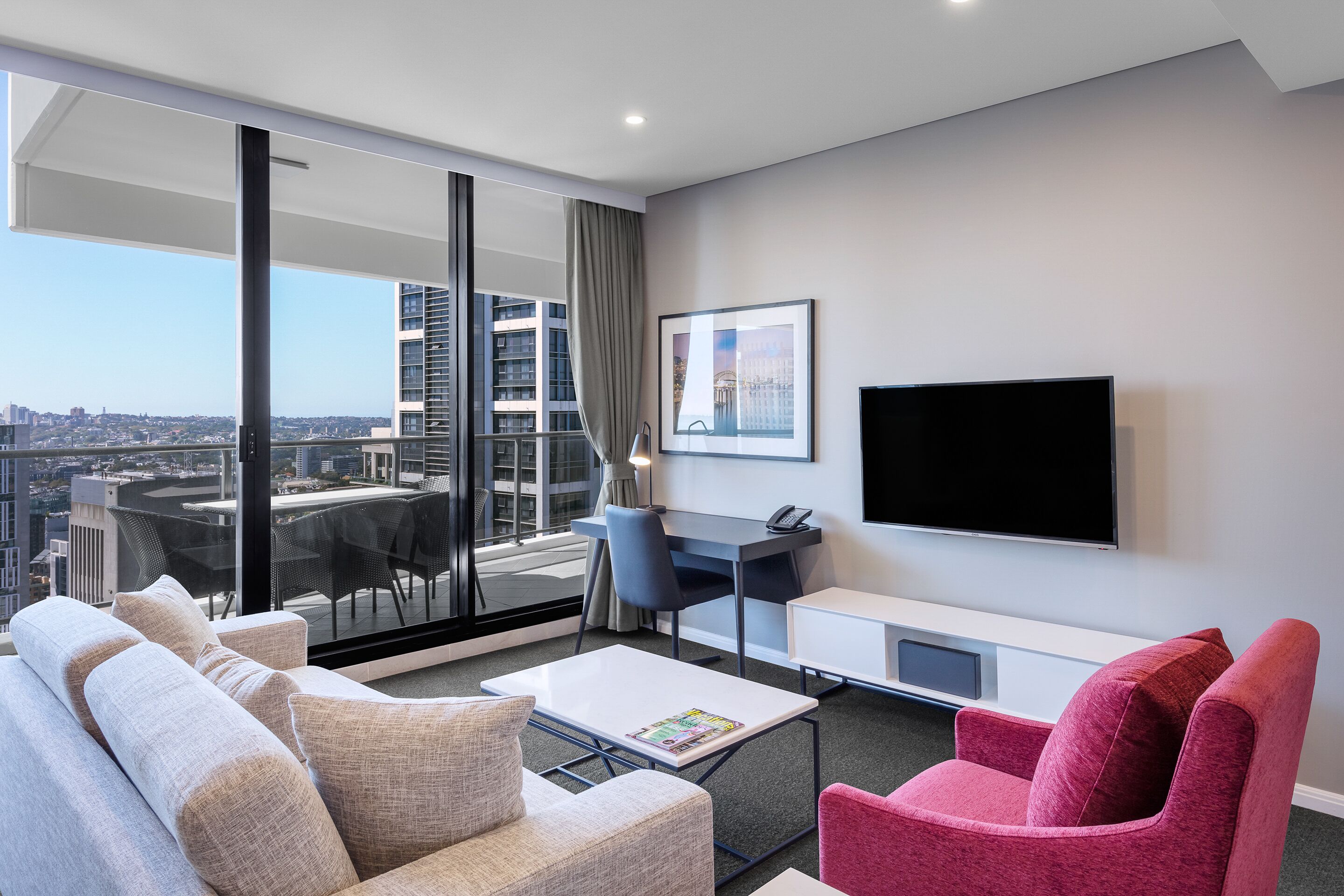 Une chambre d’hôtel moderne dotée d’une grande fenêtre, d’un téléviseur à écran plat, d’un bureau et d’un canapé.