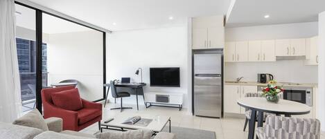 A modern living room with a sofa, a red chair, a coffee table, and a TV.