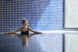 Una persona en una piscina con un muro de azulejos al fondo.