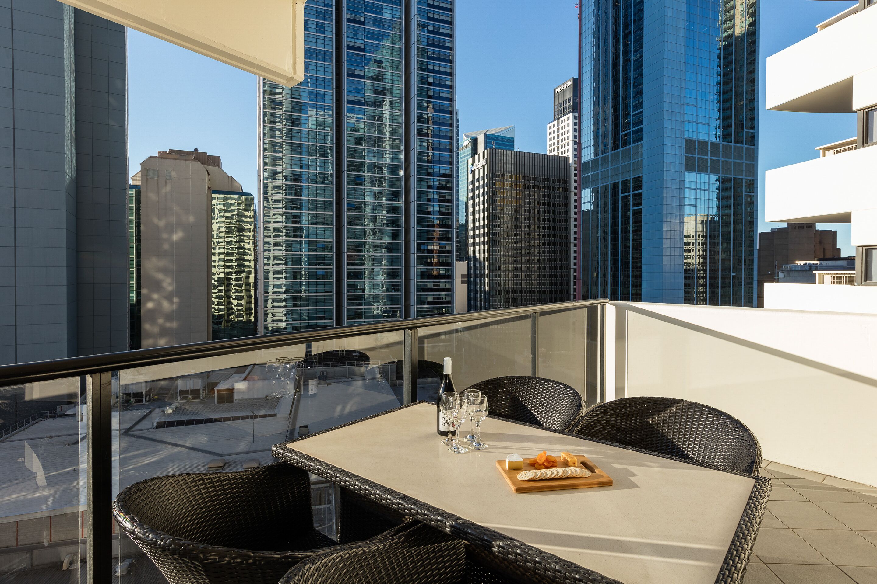A balcony with a table, chairs, and a bottle of wine.