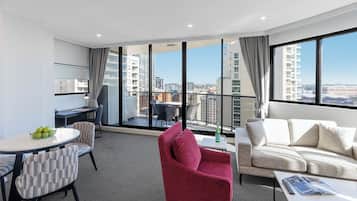A modern hotel room with a balcony, a dining area, and a sofa.