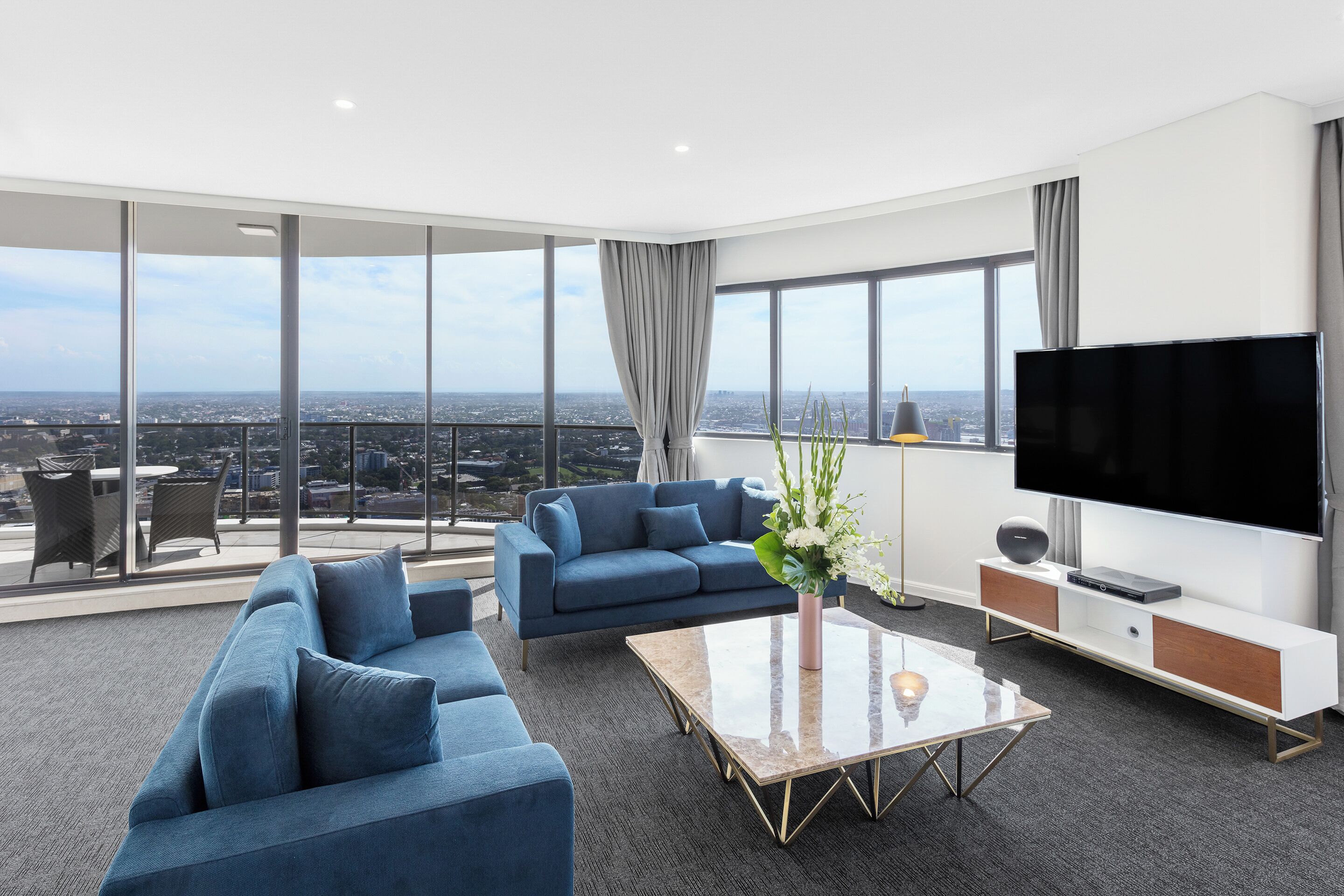 A modern living room with a sofa, coffee table, TV, and a city view.