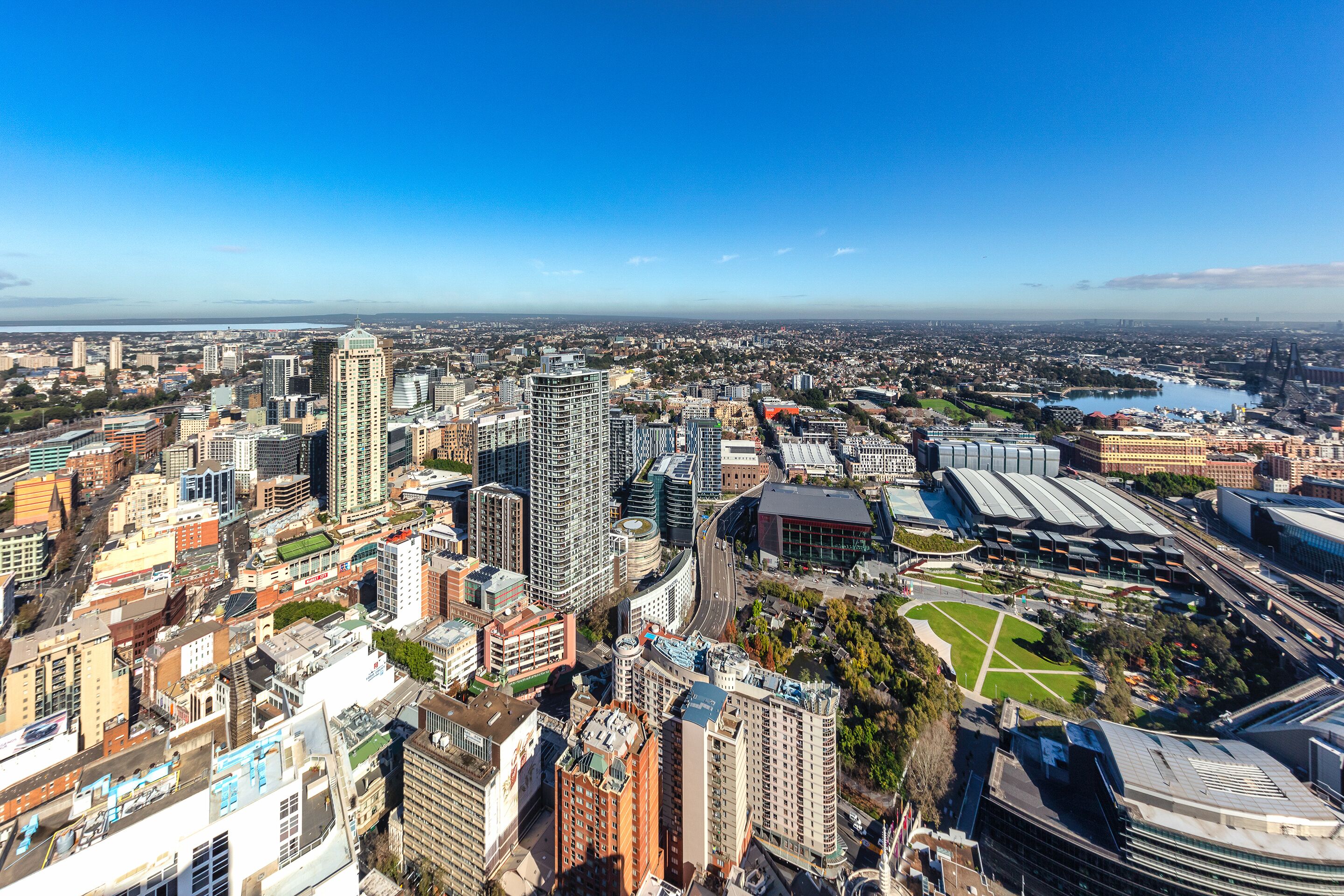 A cityscape with high-rise buildings, a stadium, and a river.