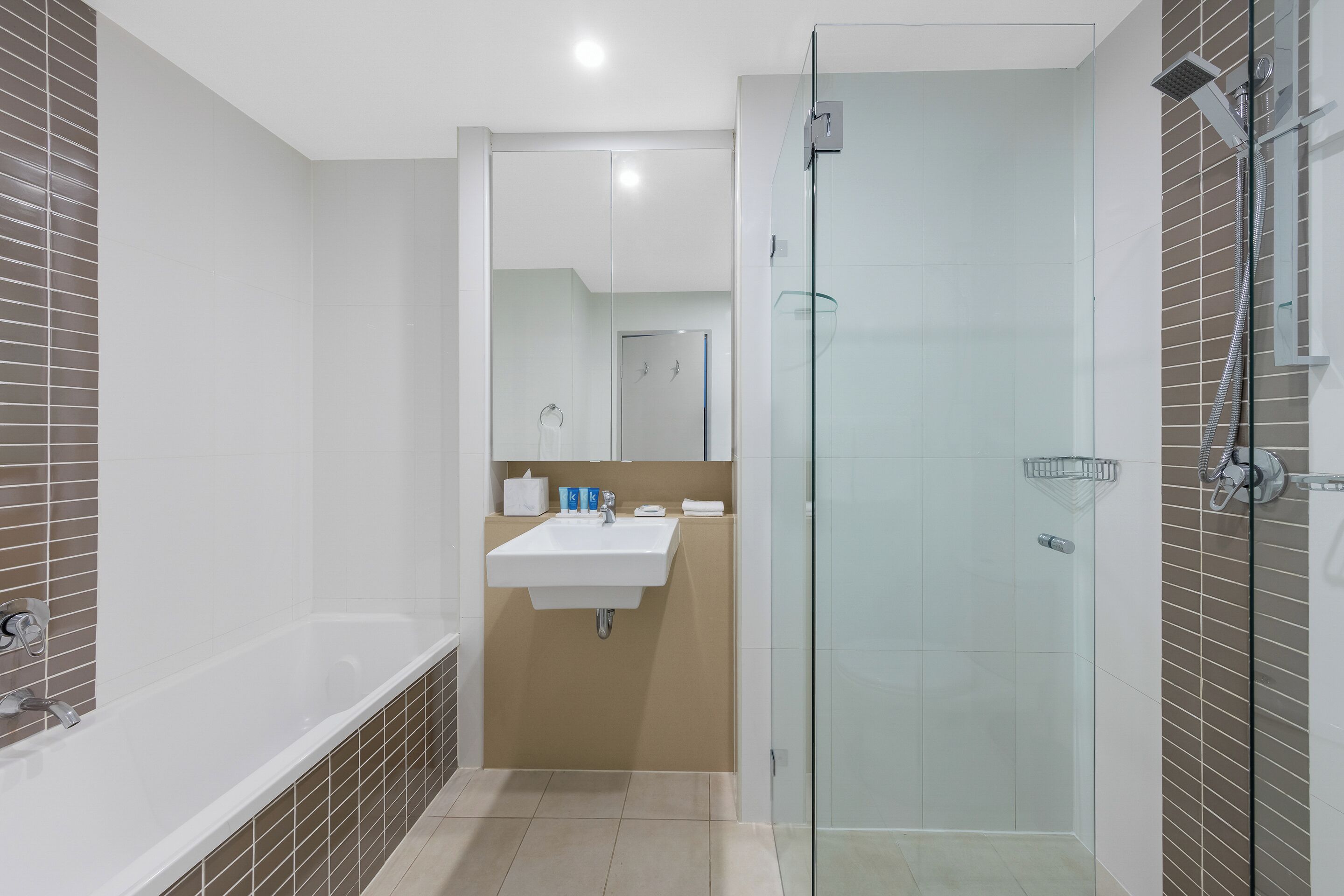 A modern bathroom with a bathtub, sink, and glass shower enclosure.