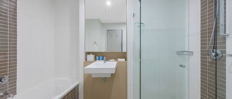 A modern bathroom with a bathtub, sink, and glass shower enclosure.