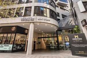 Das äußere Erscheinungsbild des Meriton Suites an der Kent Street, mit modernem Design, großen Fenstern und einem markanten Eingang.