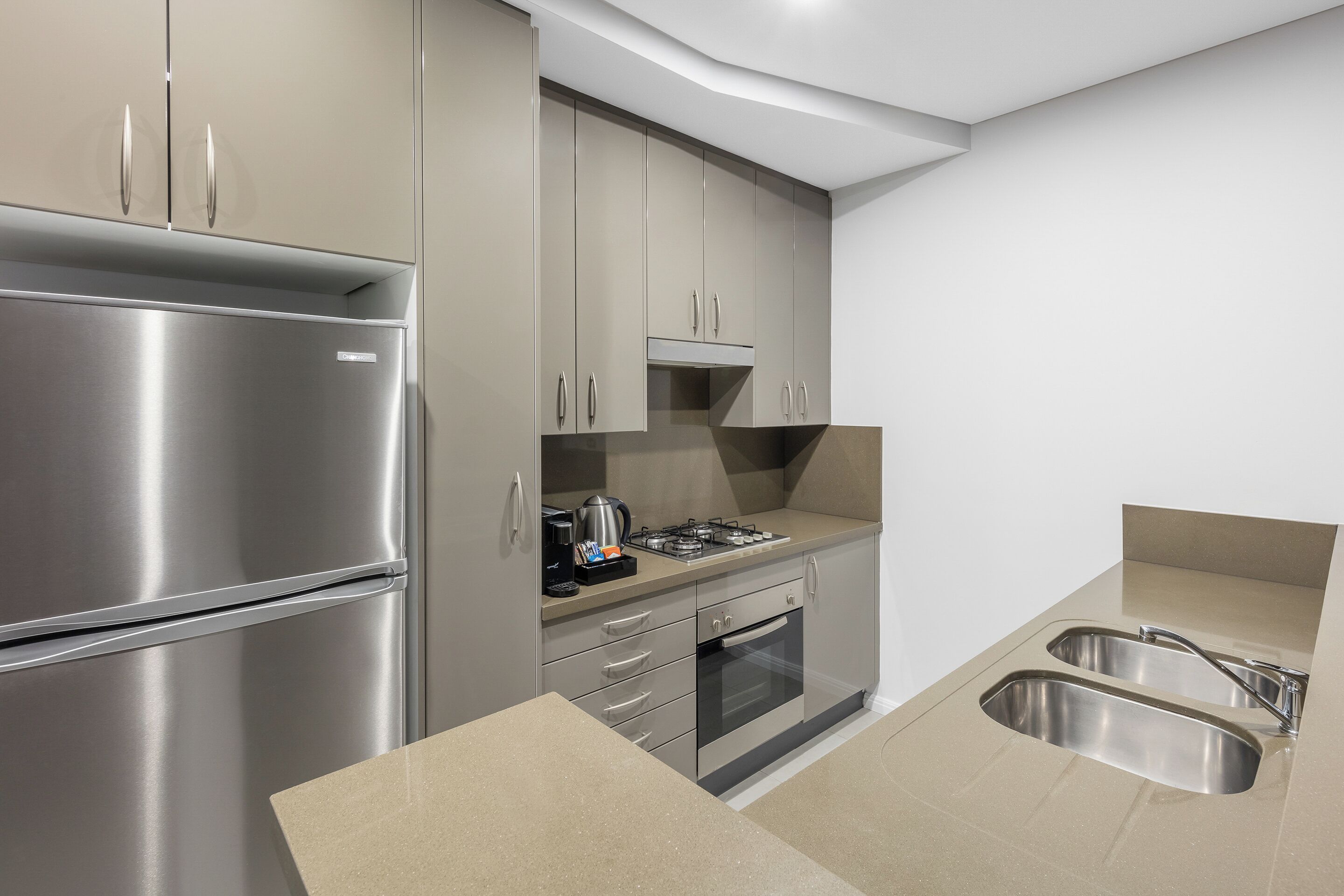 Una cocina moderna con electrodomésticos de acero inoxidable, estufa a gas y un lavamanos doble.