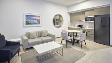 Una sala de estar moderna con un sofá gris, una mesa de centro blanca y un comedor con sillas y una mesa.