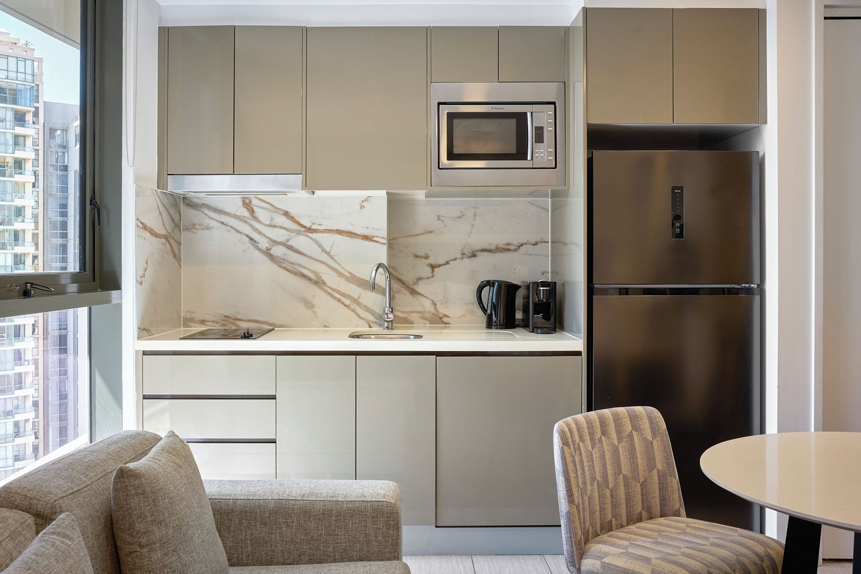 A modern kitchen with a marble backsplash, stainless steel appliances, and a built-in microwave.
