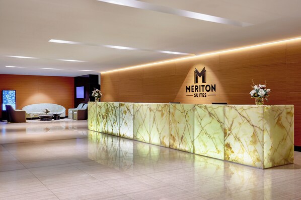 Una recepción con encimera de mármol, logotipo y diseño de interiores moderno.