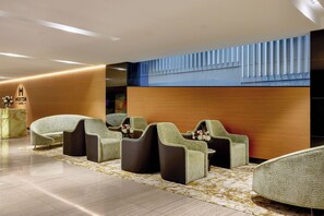 Un moderno vestíbulo de hotel con áreas de estar, un mostrador de recepción y una pared decorativa.