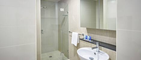 A modern bathroom with a glass-enclosed shower, a white sink, and a mirror above it.