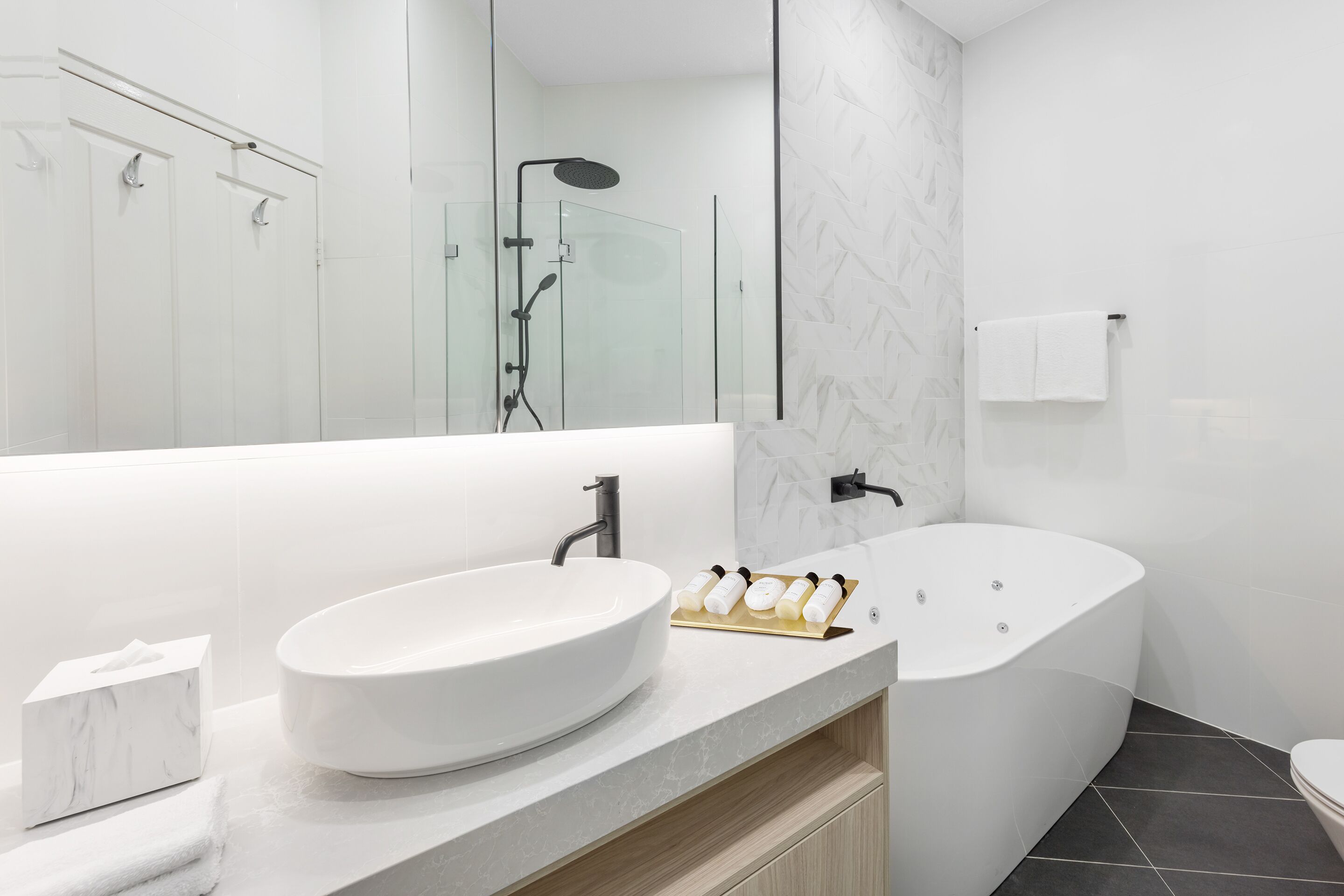 A modern bathroom with a large white sink, a freestanding bathtub, and a glass-enclosed shower.