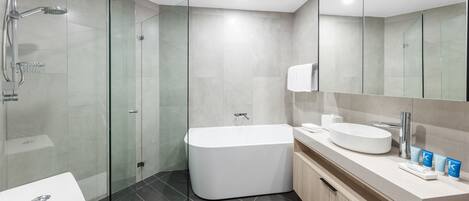 A modern bathroom with a glass-enclosed shower, a freestanding bathtub, a sink, and a mirror.