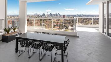A modern office space with a large table and chairs, a city view, and a balcony with a railing.