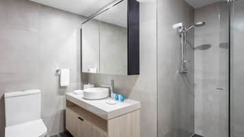 Un bagno moderno con vaso, lavabo, specchio e doccia.