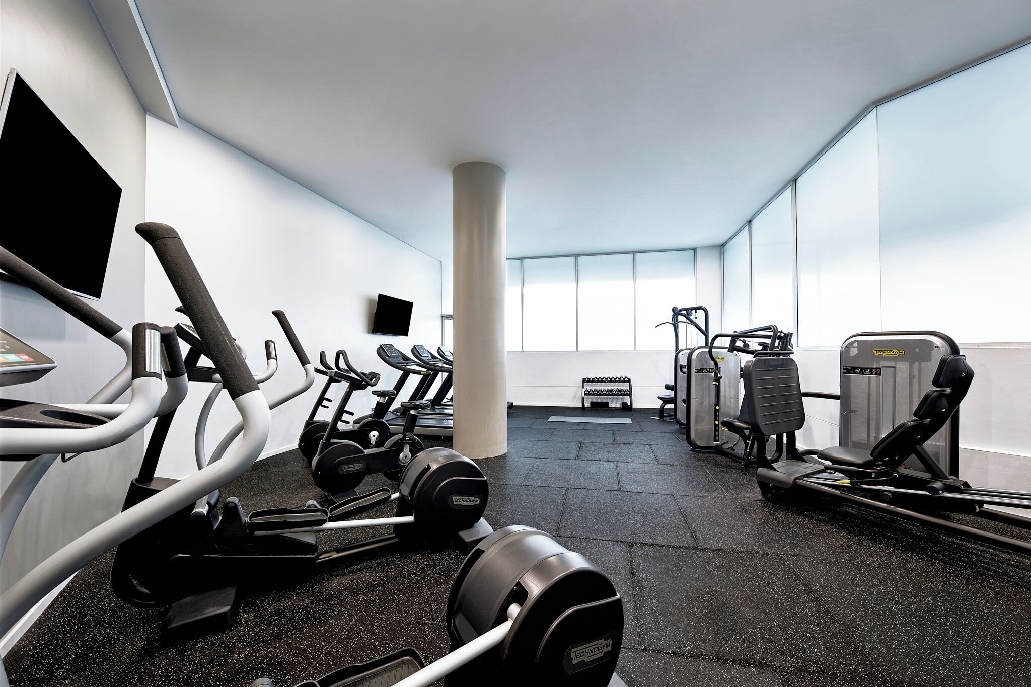 Una palestra moderna con tapis roulant, macchinari per pesi e pesi liberi.