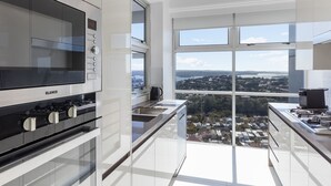 A modern kitchen with a BLANCO oven, a large window with a city view, and a high ceiling. - Meriton Suites Bondi Junction (Bondi Junction)